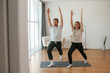 © standret - Warrior asana. Man and woman are doing yoga exercises at home