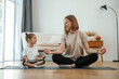 © standret - Smiling, positive facial expression. Young woman with little girl are doing yoga at home