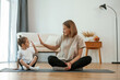 © standret - Smiling, positive facial expression. Young woman with little girl are doing yoga at home