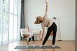 © standret - To the side, stretching. Young woman with little girl are doing yoga at home