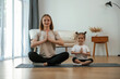 © standret - Calm, in lotus pose. Young woman with little girl are doing yoga at home