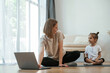 © standret - Using laptop. Young woman with little girl are doing yoga at home