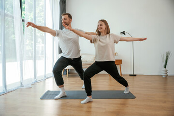 Sticker - Warrior asana. Man and woman are doing yoga exercises at home