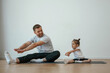 © standret - Teaching how to stretch the legs. Father with little daughter are doing yoga at home
