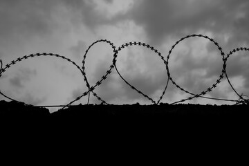 Prison wall and barbed wire with dramatic clouds behind. Law and justice, jail or freedom concept