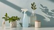 © khunnapat - A minimalist composition with a blue spray bottle, potted plants, and a ceramic jar, bathed in soft sunlight against a light blue wall.