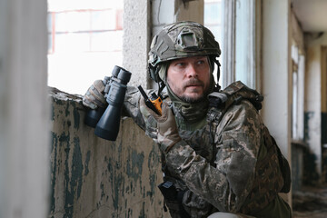 Wall Mural - Military mission. Soldier in uniform with binoculars inside abandoned building