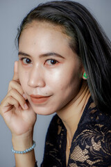 portrait of an Indonesian woman wearing a black kebaya in the studio with a disheveled pose isolated white background