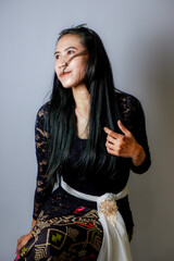 portrait of an Indonesian woman wearing a black kebaya in the studio with a disheveled pose isolated white background