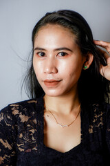 Wall Mural - portrait of an Indonesian woman wearing a black kebaya in the studio with a disheveled pose isolated white background