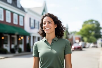 Wall Mural - Portrait of a happy woman in her 20s wearing a breathable golf polo isolated on charming small town main street