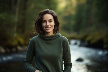 Wall Mural - Portrait of a content woman in her 30s dressed in a comfy fleece pullover isolated in tranquil forest stream