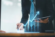 © kenchiro168 - Businessman using tablet to analyze digital rising financial graph, indicating business growth and success.