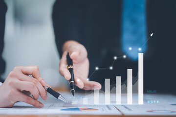 Close-up of business professionals analyzing and discussing data on growth chart, highlighting business performance and success.