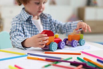 Poster - Little boy playing with toy cars at white table in kindergarten, closeup