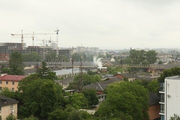 Canvas Print - Picturesque view of city with buildings and construction cranes on cloudy day