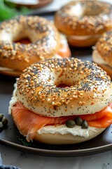 Wall Mural - Bagel with Smoked Salmon: A bagel topped with cream cheese, thin slices of smoked salmon, capers, and a sprinkle of fresh dill, presented on a dark plate.