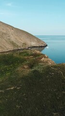 Wall Mural - The long slope of the mountain.The view from the drone. Shot.Beautiful view of the blue clear sea and the huge mountains above it with small white residential buildings.