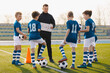 © matimix - Football tactics training for children. Boys with a coach on the football field. Coach talking about the game plan. Trainer using tactics board to explain soccer game strategy