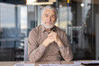 © Liubomir - Senior businessman sitting in a modern office environment confidently with folded hands. The mature professional exudes experience and wisdom. Ideal for business, executive, leadership