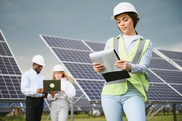 Group of investors together with young lady ecological engineer they analysing the plan of work and the efficient operation of solar batteries