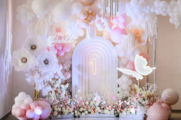 Wall Mural - Arch decorated pink, white balloons, text Happy Birthday, flowers, paper decor butterfly. Birthday party for 1 year old girl on a background photo wall. Children's photo zone.