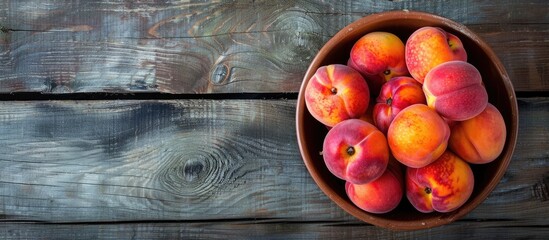 Poster - Top view of peaches in a bowl on a rustic wooden table with copy space image.
