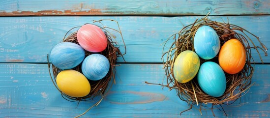 Sticker - Colorful Easter egg in a nest on blue pastel color wood background with copy space image.