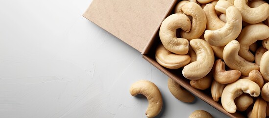 Wall Mural - An image showcasing a close-up of a cashew nut in a brown box on a white background, emphasizing the healthy food concept and allowing for text to be added in the available space.