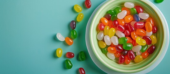 Sticker - Colorful jelly beans on a plate on a green surface with copy space image, a popular Easter treat.