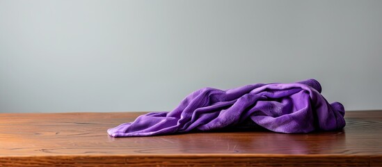 Sticker - A purple cloth or towel lies on a brown table, isolated against a white backdrop with a copy space image.