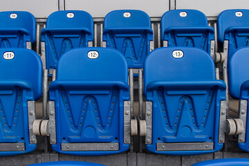 Plastic folding seats at the city stadium. Numbered seats, blue color, empty plastic seats, tribune.