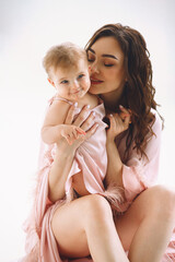 Portrait happy mother hugging her baby girl. Mommy and daughter in same fashionable dresses. Mothers love