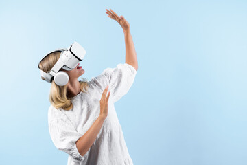 Wall Mural - Skilled girl in pajamas excited with metaverse by using VR goggle at background. Caucasian woman surprised while looking around at futuristic view looking though visual reality goggles. Contraption.