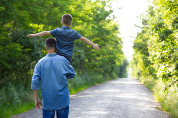 Poster - A Happy child on the shoulders of a parent in nature on the way to travel