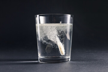 Wall Mural - Effervescent pill dissolving in glass of water on grey table