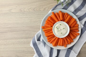 Wall Mural - Baby carrots and sauce on wooden table, top view. Space for text