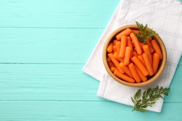 Poster - Baby carrots and green leaves on light blue wooden table, top view. Space for text