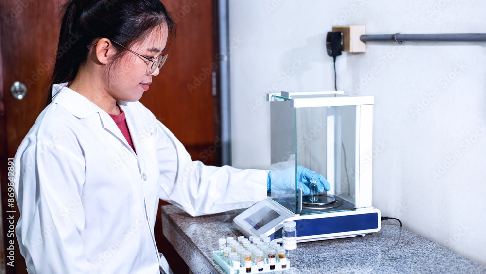 A scientist in a white lab coat and blue gloves is using an analytical ...