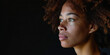 © Maestro - Close-up portrait of thoughtful young woman with curly hair and freckles against dark background