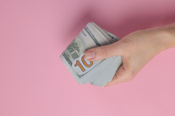 Wall Mural - Money exchange. Woman holding dollar banknotes on pink background, top view