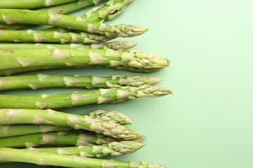 Sticker - Fresh asparagus stems on green table, top view. Space for text