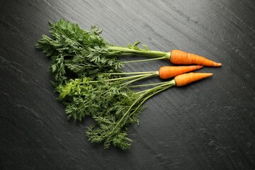 Wall Mural - Tasty ripe juicy carrots on dark gray textured table, top view