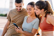 © Xavier Lorenzo - Three young sportive friends using mobile phone after workout routine outdoor. Technology lifestyle and fitness concept