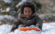 © imagineRbc - A young, mixed race boy wearing a brown winter coat sits on a bright orange sled in a snowy landscape. He smiles brightly for the camera