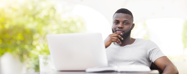 Poster - A man with a beard sits in front of a laptop, thinking about his work.