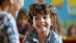 © Nicholas - A young boy with curly hair is smiling in a classroom setting, interacting with his classmates, creating a cheerful and engaging learning environment.
