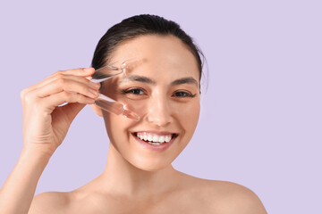 Poster - Beautiful young woman with ampules on lilac background, closeup