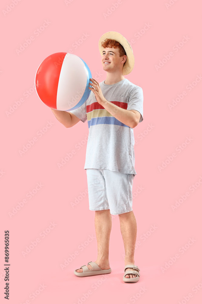 Young man with beach ball on pink background