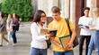 © Prostock-studio - Student couple going to college class, reading book outdoors in university campus